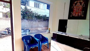 A room with a large window, a TV, and a wall-mounted cabinet. - PPH Living Royal Pride (Madurai)