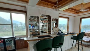 A kitchen with a bar area, large windows, and a view of the mountains. - ABHILASHI INN (Balh)