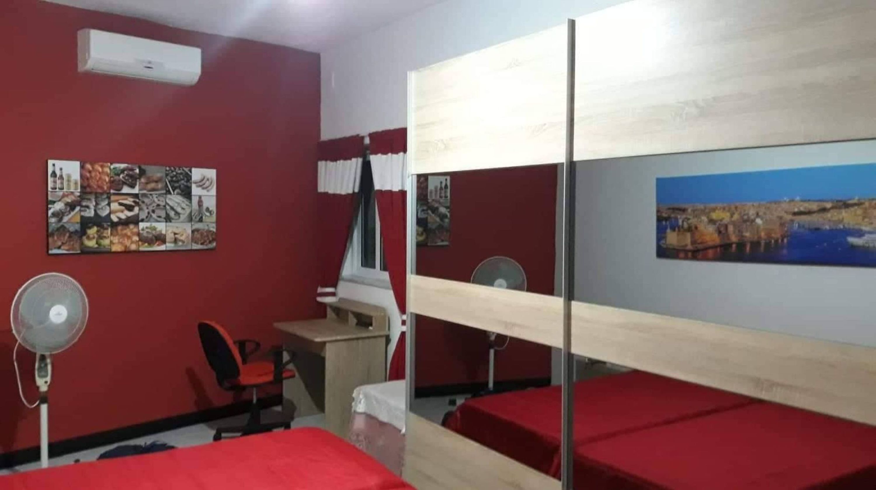 Una stanza con letti a castello, una scrivania, una sedia e un ventilatore.