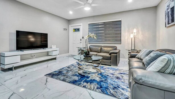 A modern living room with a flat-screen TV, leather sofa, and a coffee table.