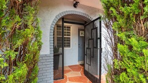 A house entrance with a stone pathway, a black door, and a window.