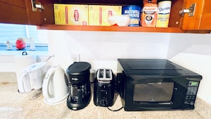 Eine Küche mit Kaffeemaschine, Toaster und Mikrowelle auf der Arbeitsfläche.