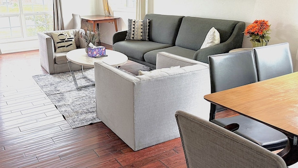 Ein modernes Wohnzimmer mit einer Eckcouch, einem runden Couchtisch und einem Essbereich mit Holztisch und Stühlen.