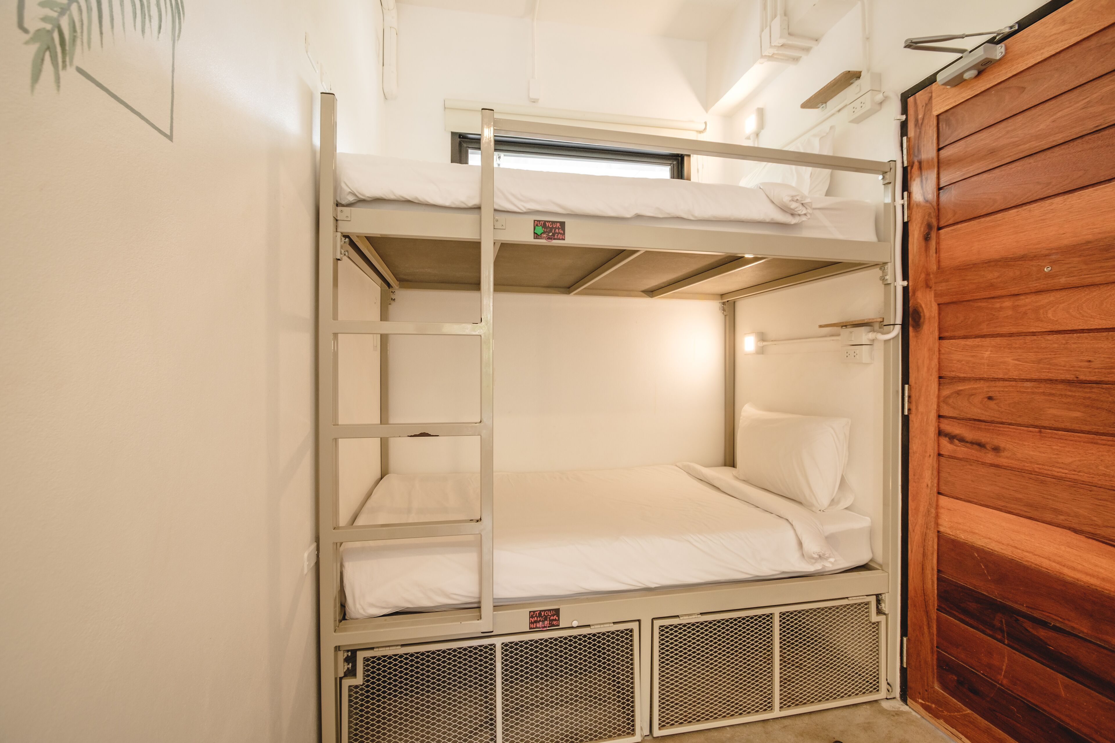 A bunk bed with a ladder, a wooden door, and a small window.