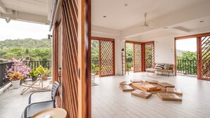 Un balcon spacieux avec des balustrades en bois, un coin salon avec des coussins et des plantes en pot.