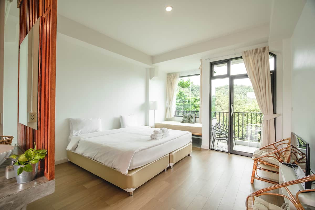 Ein Schlafzimmer mit Bett, Fernseher, Balkon und Fenster.