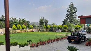 A residential area with a well-maintained lawn, a row of potted plants, and a parked pickup truck. - HOTEL DHARAMSHALA PARADISE (Dharamshala)