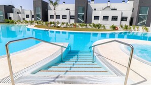 A swimming pool with steps leading into it, surrounded by modern buildings with large windows.