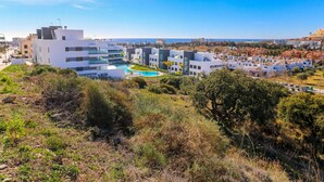 A modern residential area with a pool, white buildings, and a clear view of the sea.