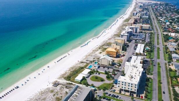 Vista aérea de una zona costera con playa, edificios y una carretera.
