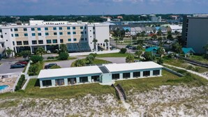 Un hotel con un edificio alargado, estacionamiento y una zona de playa.