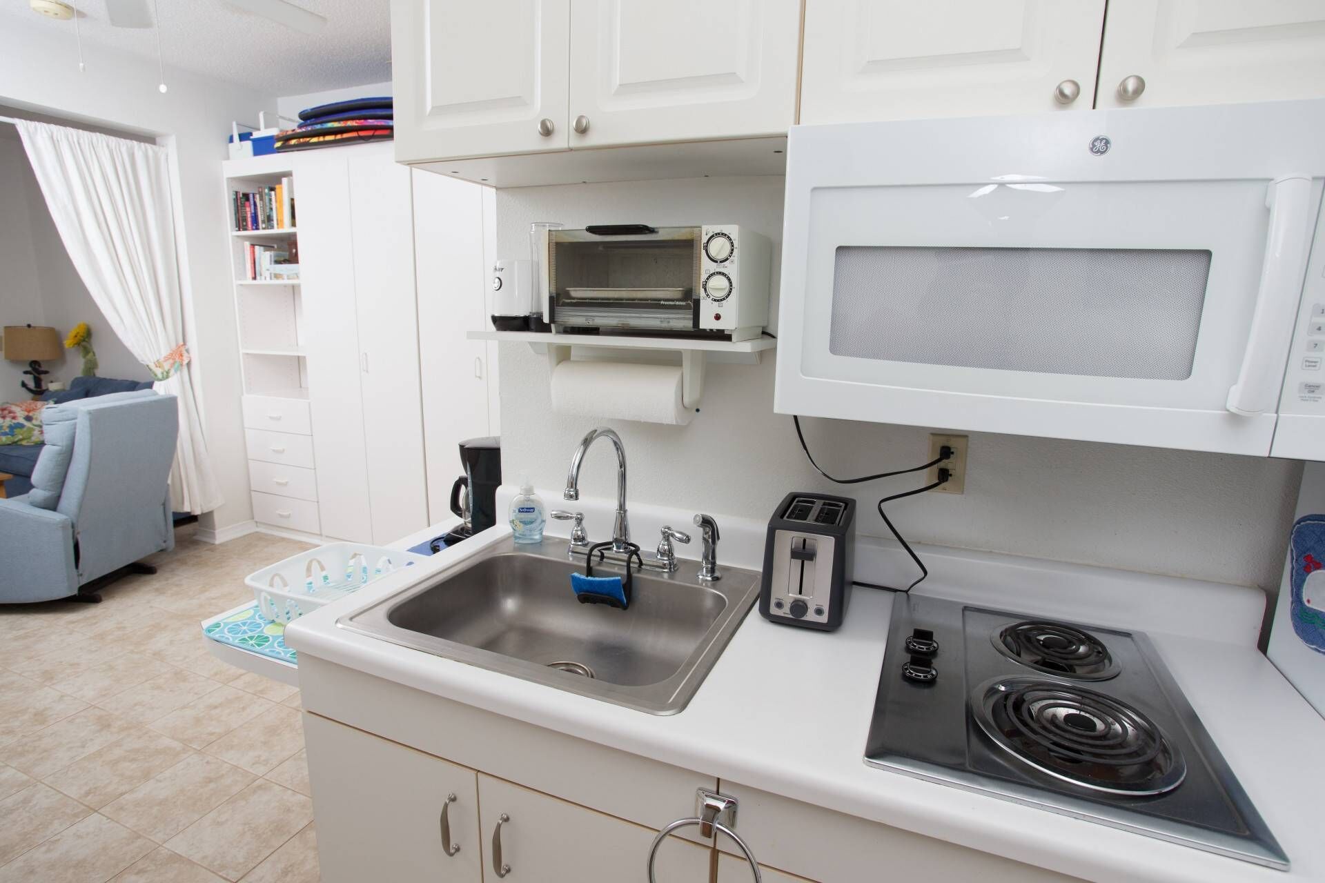 A compact kitchen with a sink, toaster, microwave, and stove.