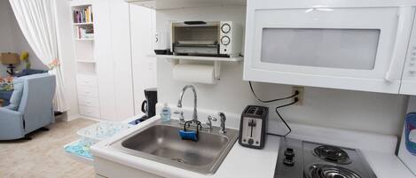 A compact kitchen with a sink, toaster, microwave, and stove.