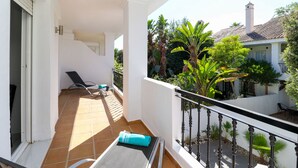 A balcony with a tiled floor, a chair, a towel, and a railing.