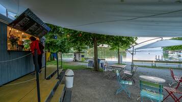 Ein Sitzbereich im Freien mit Seeblick, Tische, Stühle und einer Speiseausgabe.