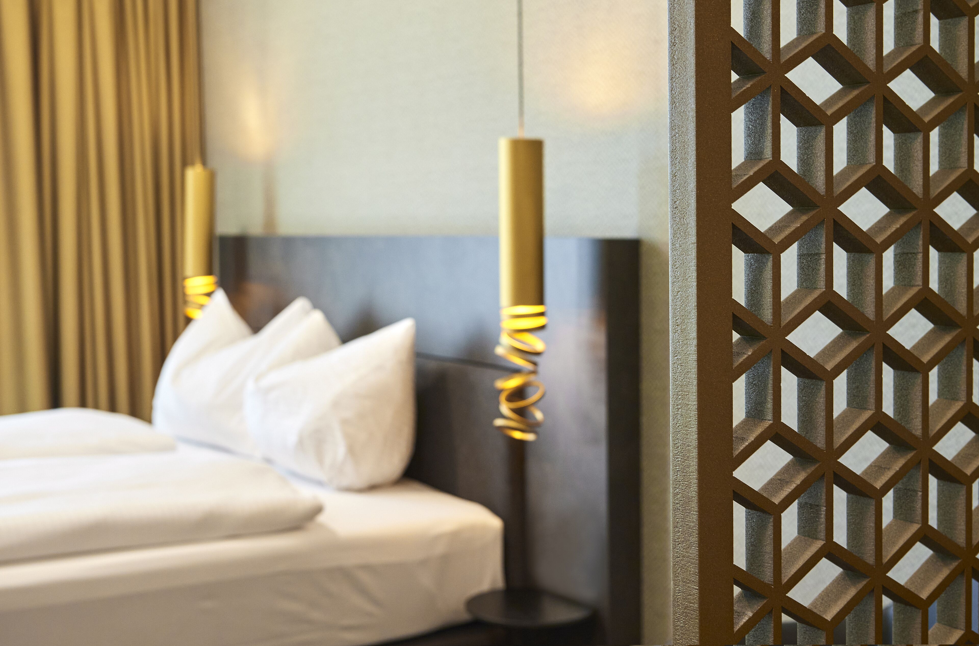 Quarto de hotel com uma cama, almofadas, abajur e um ecrã decorativo.