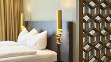 Quarto de hotel com uma cama, almofadas, abajur e um ecrã decorativo.