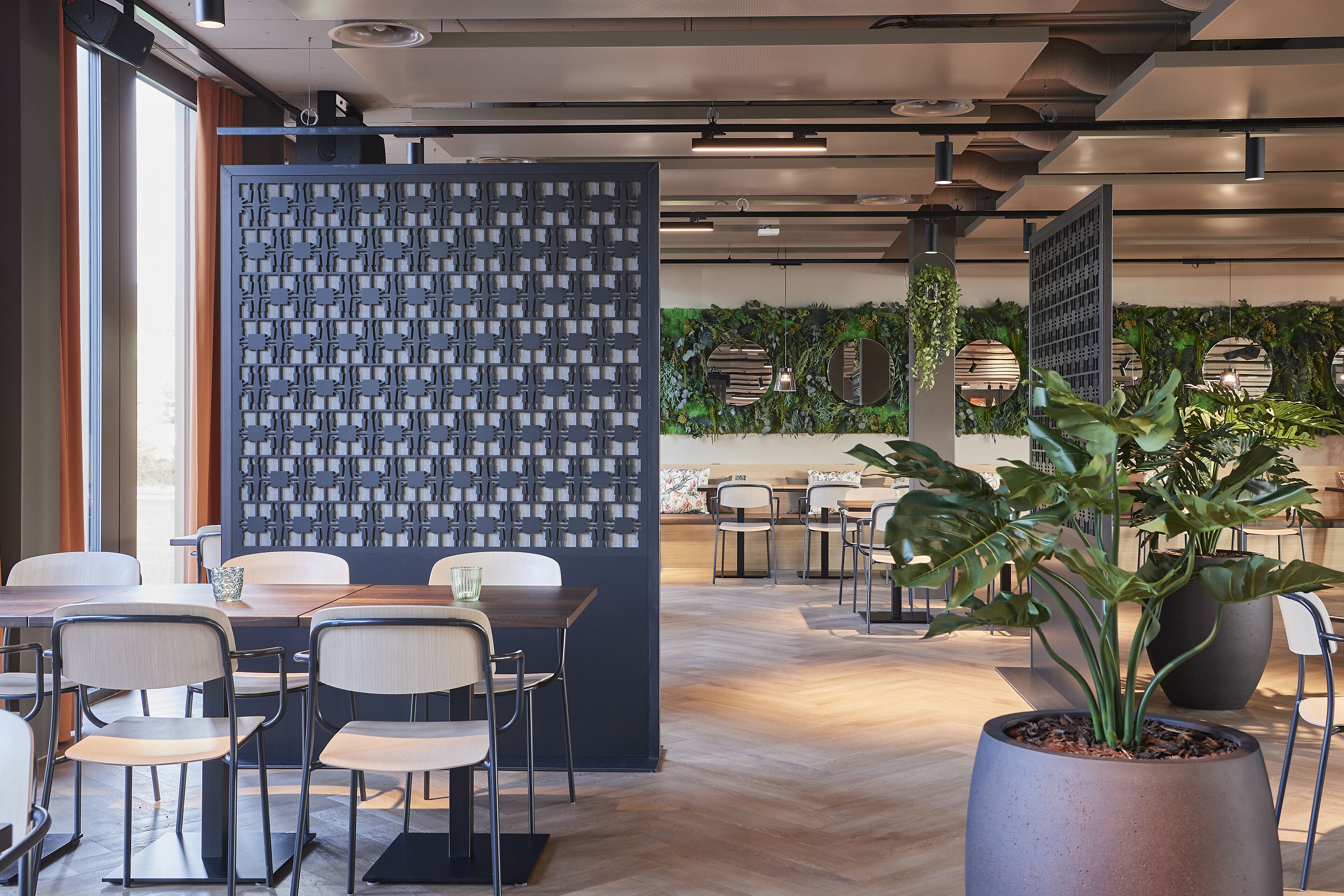 Een moderne kantoorruimte met een houten tafel en stoelen, een decoratieve wand en potplanten.