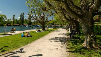 A park with a dirt path, benches, and people sitting on the grass.