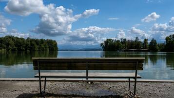 A bench by a lake with trees and mountains in the background.