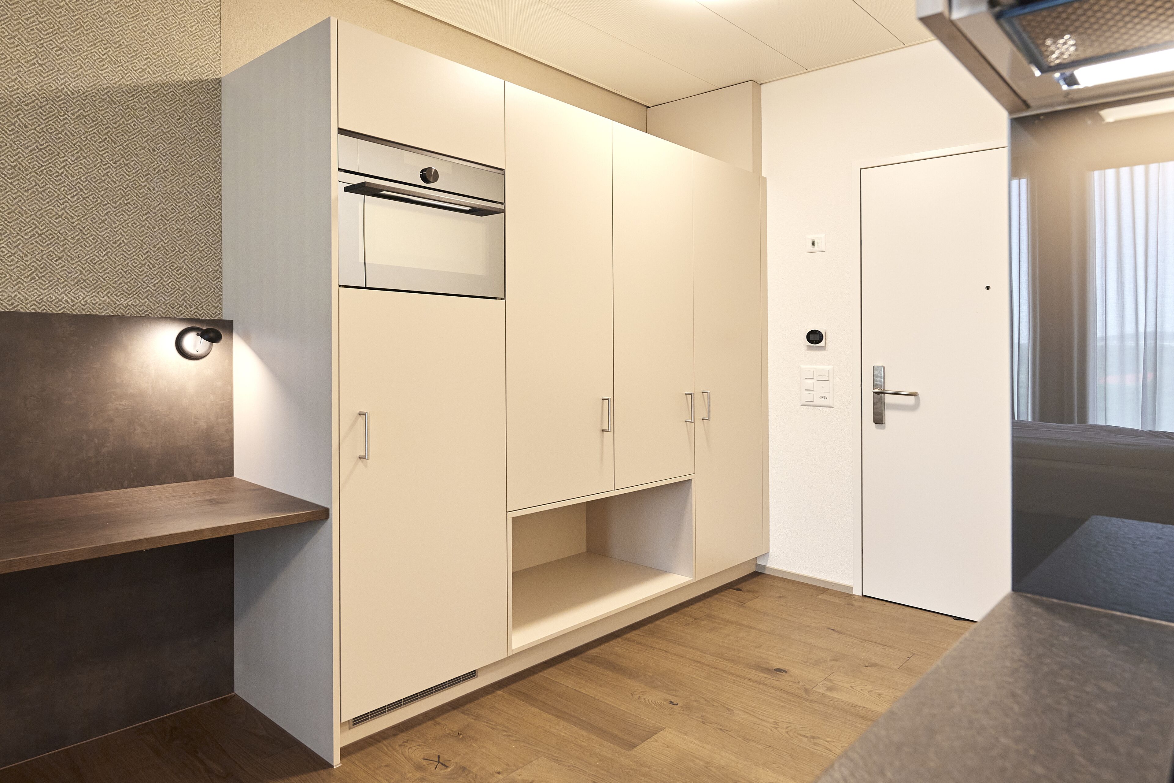 A modern kitchen with white cabinetry, a built-in oven, and a wooden countertop.