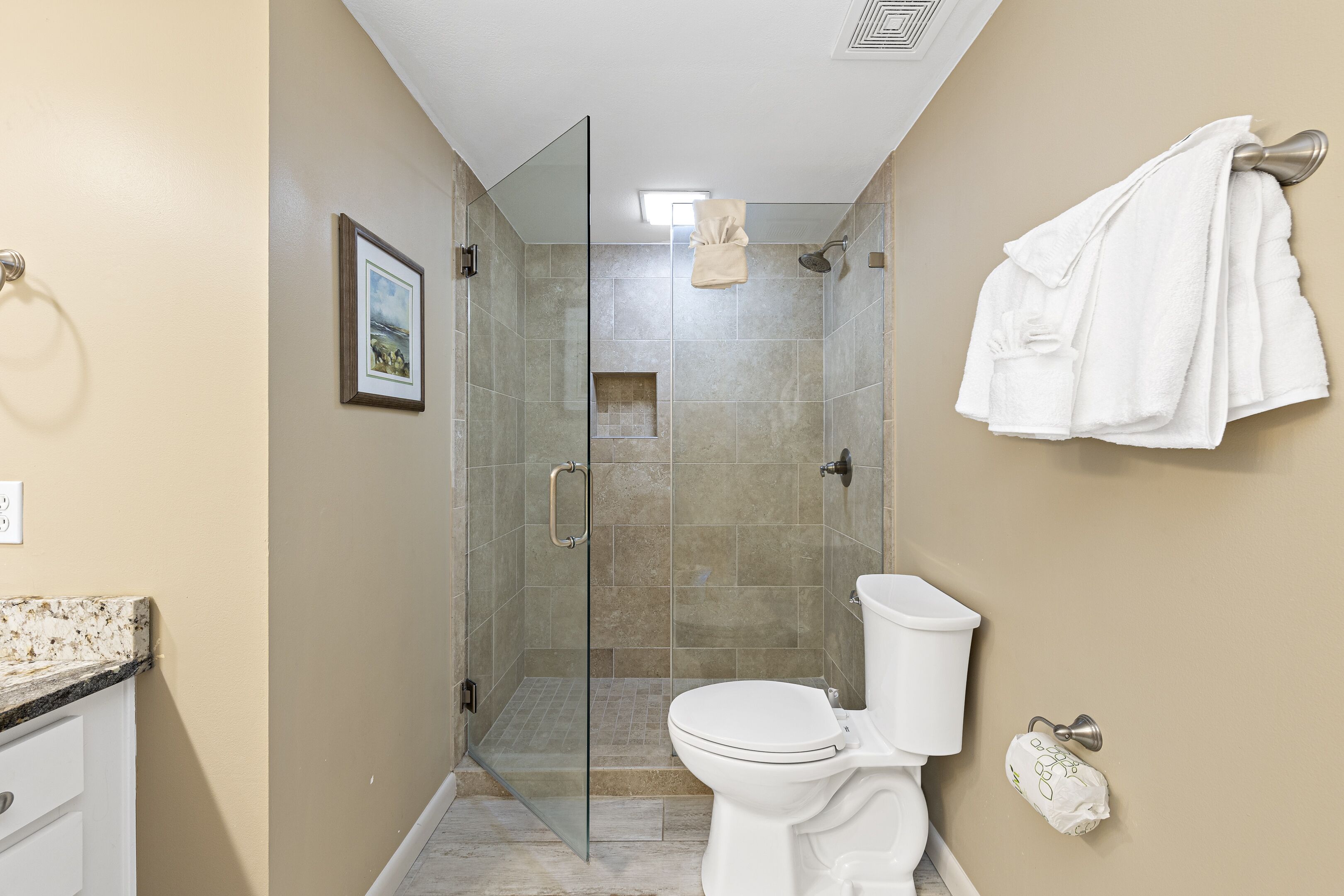 A bathroom with a glass-enclosed shower, a toilet, and a towel rack.