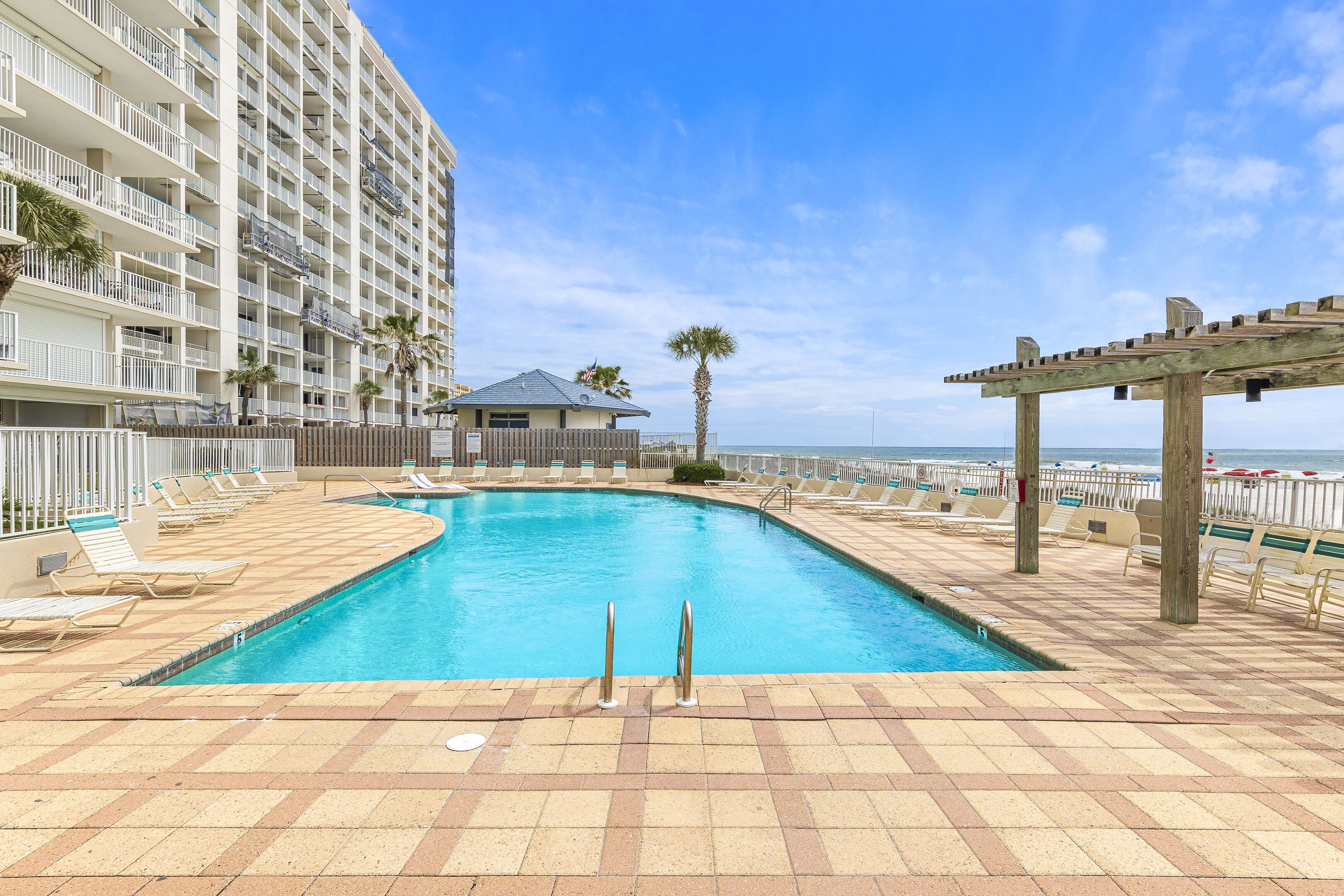 A swimming pool with lounge chairs and a view of a tall building.