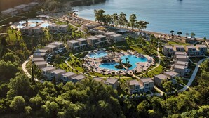 Un complexe hôtelier comprenant plusieurs bâtiments, un espace piscine central et une plage.