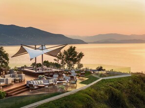 A terrace with outdoor seating and a view of the sea. - Ikos Odisia - All Inclusive (Corfu)
