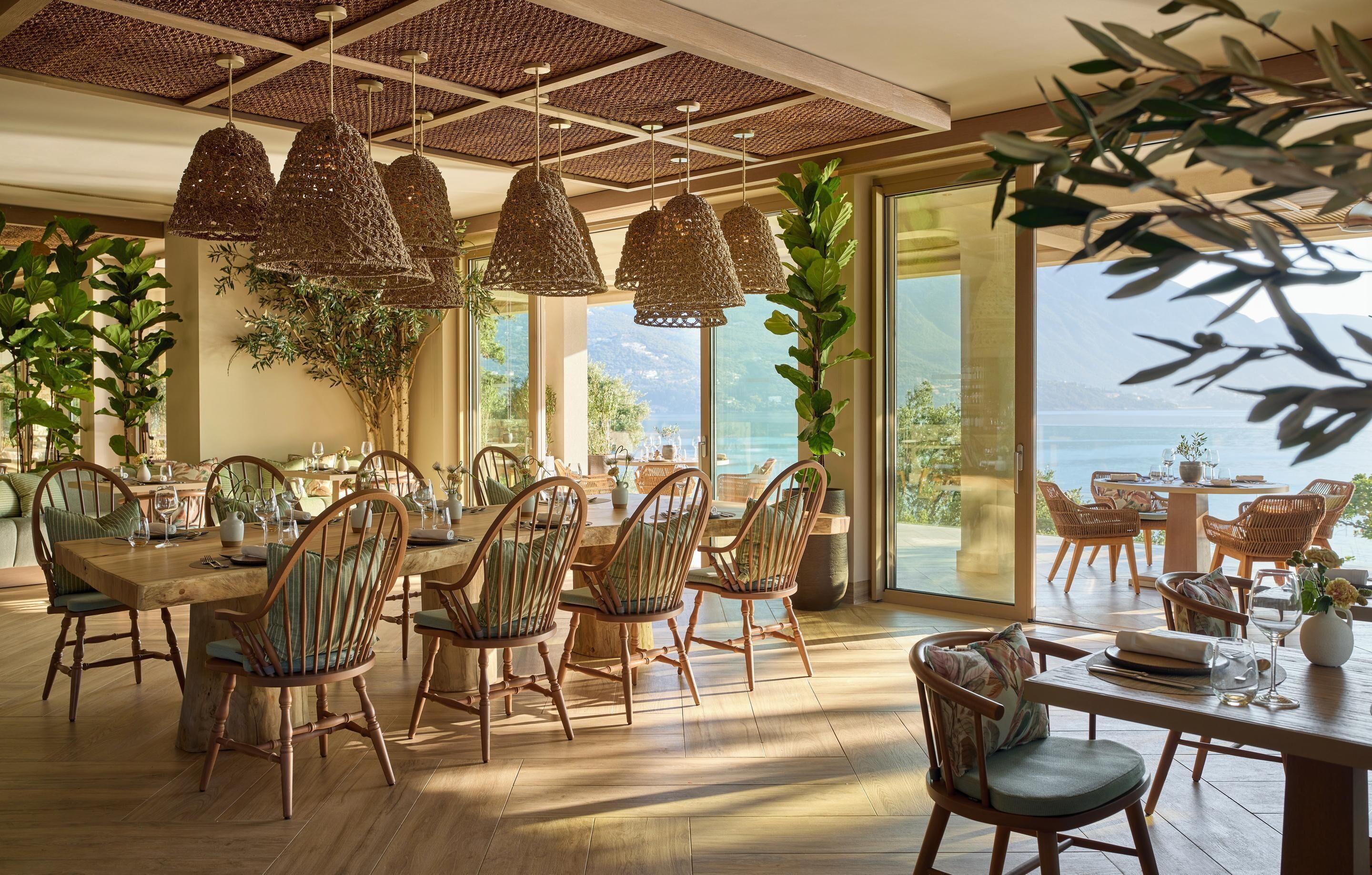 A dining area with wicker chairs, a wooden table, and hanging wicker lamps.
