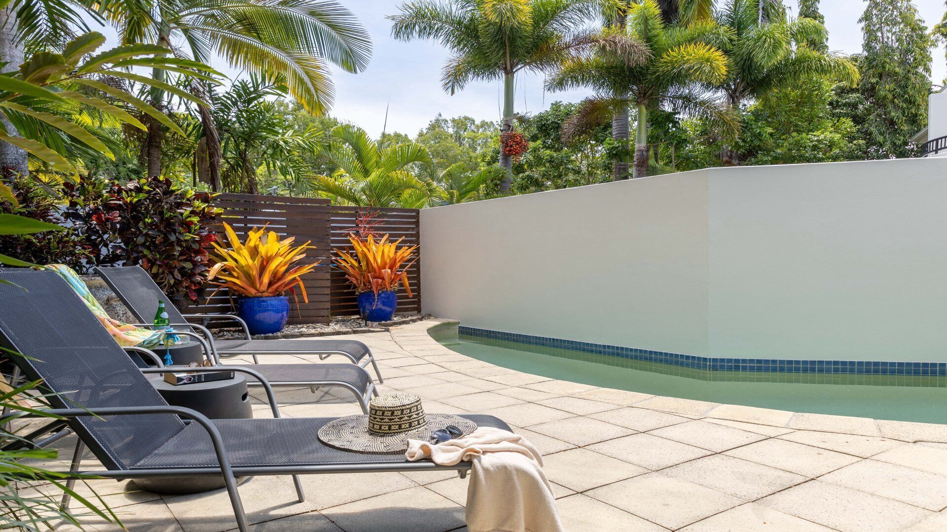 Un espace aménagé au bord de la piscine, avec des chaises longues et des plantes en pot.