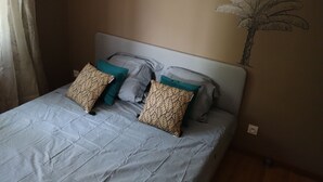 A neatly made bed with patterned pillows and a wall mural. - Gîte en Pleine Nature (Valaurie)