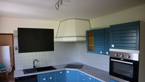 A kitchen with blue cabinets, a black dishwasher, a stainless steel oven, and a black sink. - Gîte en Pleine Nature (Valaurie)