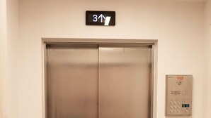Ein Aufzug mit Bedienfeld und Schild, das die dritte Etage anzeigt.