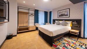 Ein modernes Hotelzimmer mit einem Bett, einem Schreibtisch, einem Sessel und einem Teppich mit Muster.