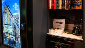 Ein Bücherregal mit Büchern, eine Neonreklame, ein Bildschirm und ein Weinkühler.