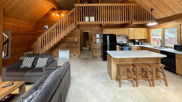 Ruime hut met een slaapkamer op entresol, een keuken met moderne apparatuur en een gezellige woonruimte met een bank en barstoelen.
