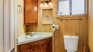 Un baño con paneles de madera, un lavabo, un espejo y un inodoro.
