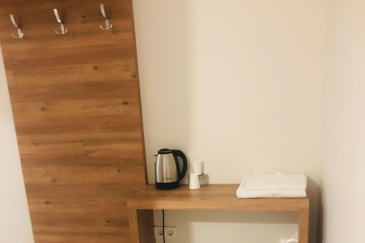 A small wooden desk with a kettle, a cup, and a folded towel.