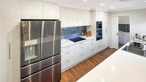 Una cocina moderna con electrodomésticos de acero inoxidable, armarios blancos y suelo de madera.