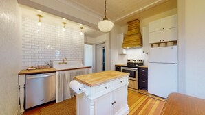 A compact kitchen with white cabinetry, a wooden countertop, a built-in oven, and a stainless steel refrigerator. - Retha Victorian - Gunnison (Gunnison)