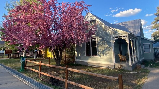A small, single-story building with a gabled roof and a porch with chairs. - Retha Victorian - Gunnison (Gunnison)