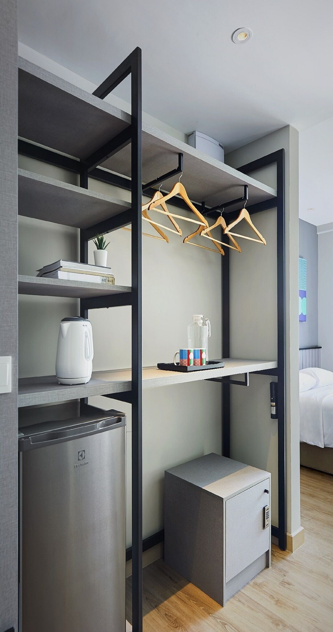 A compact hotel room with a kitchenette, a bed, and a small seating area.