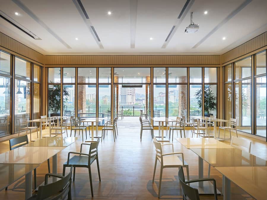 Un vaste espace dédié à la salle à manger, doté de grandes fenêtres, de meubles modernes et offrant une vue sur le paysage urbain.