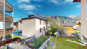 Une rue étroite, bordée de bâtiments des deux côtés, un ciel dégagé et une montagne en arrière-plan.