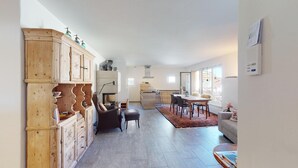 A spacious living area with a dining table, a sofa, and a kitchen in the background. - 3½ room apartment, on the second floor, with lift. (Samedan)