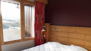 Una habitación con cama, ventana con cortinas y vista al paisaje.