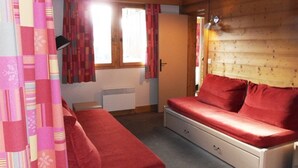 Una habitación con una cama, un radiador, una ventana con cortinas y una pared de madera.