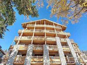 Un immeuble à plusieurs étages doté de balcons en bois et de piliers en pierre.