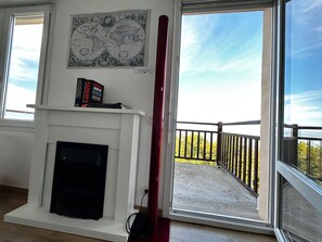 A room with a fireplace, a world map, and a balcony with a railing.